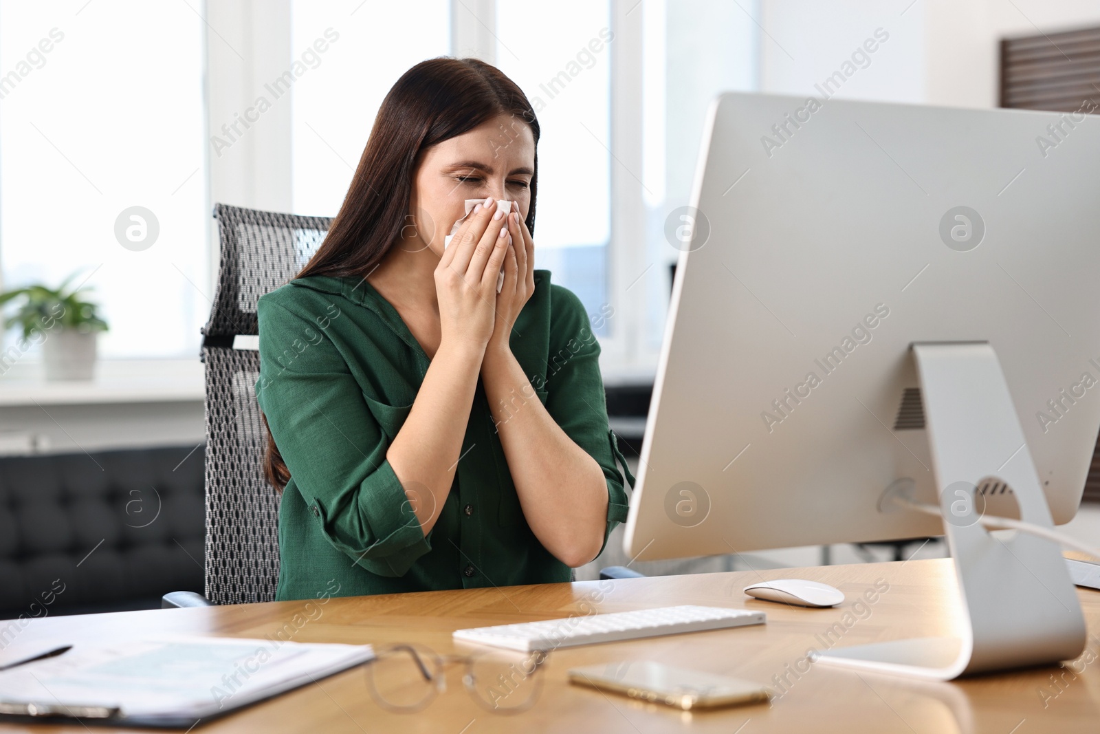 Photo of Sick woman with runny nose at table in office