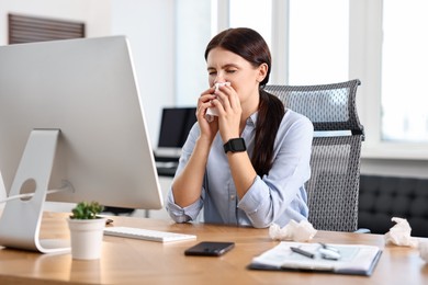 Photo of Sick woman with runny nose at table in office