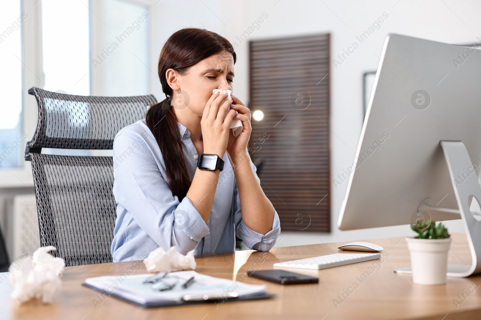 Photo of Sick woman with runny nose at table in office