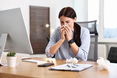 Sick woman with runny nose at table in office