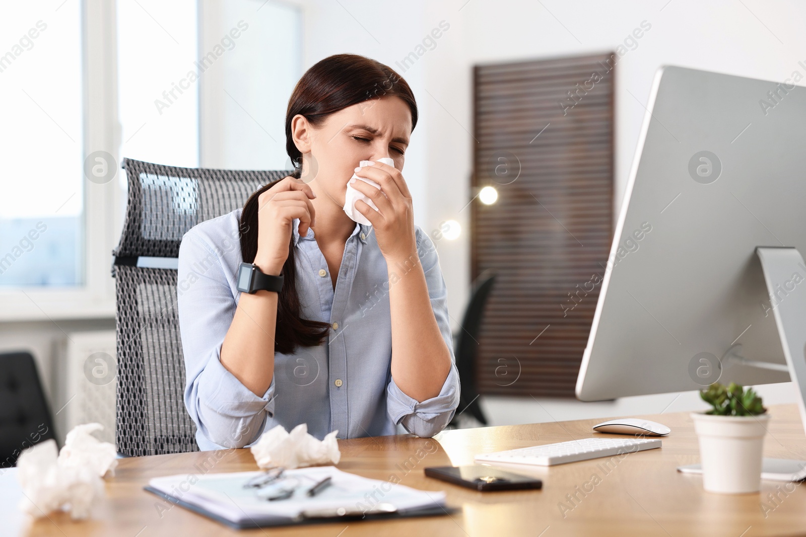 Photo of Sick woman with runny nose at table in office