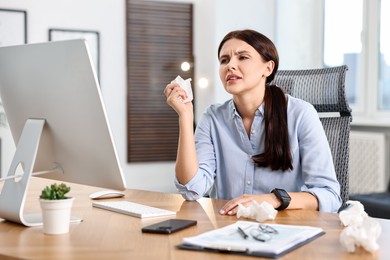 Photo of Sick woman with runny nose at table in office