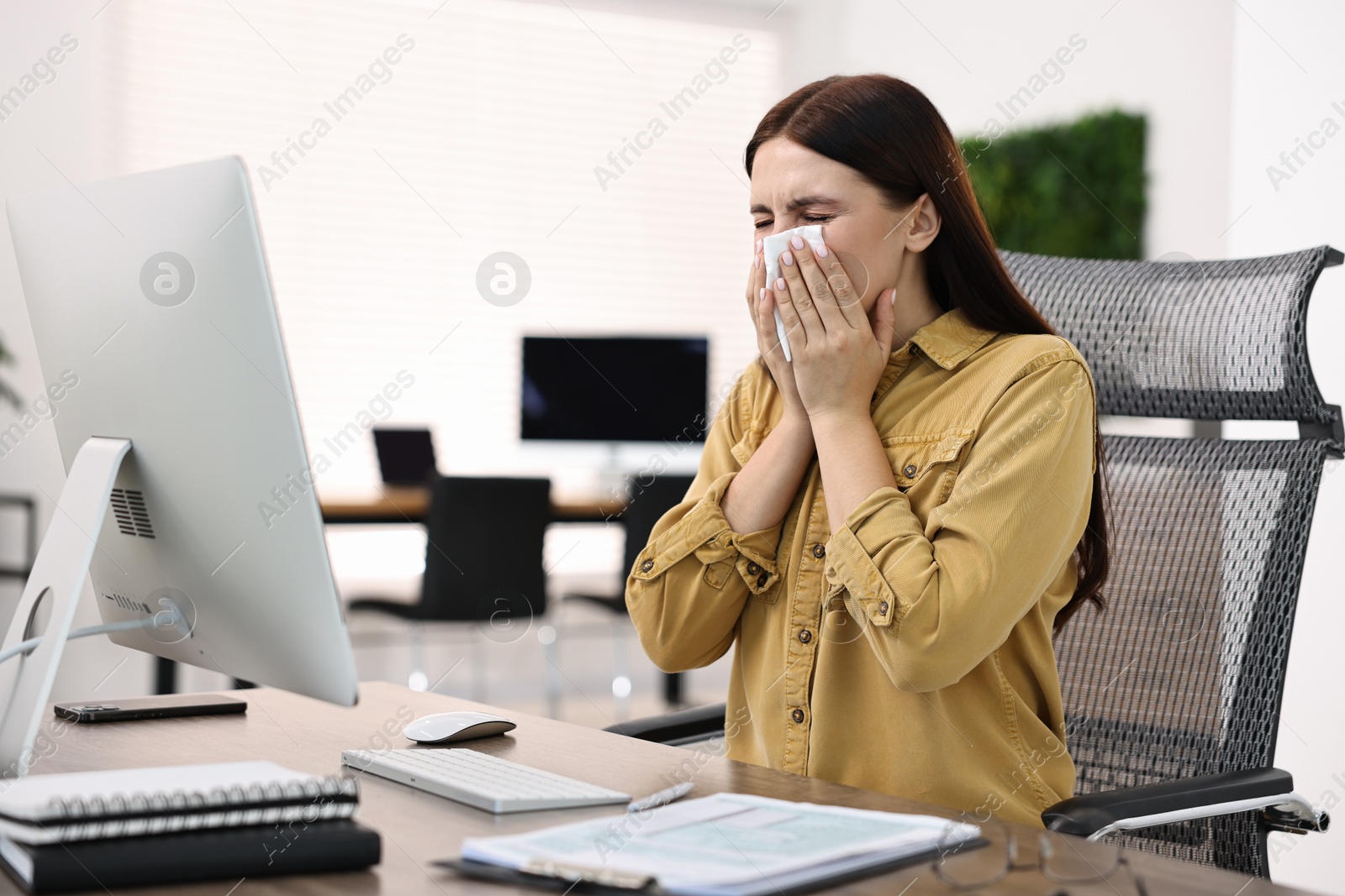 Photo of Sick woman with runny nose at table in office