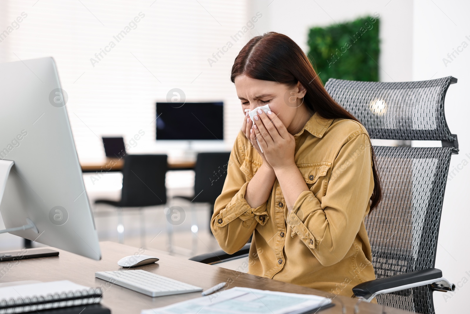 Photo of Sick woman with runny nose at table in office