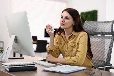 Photo of Sick woman with runny nose at table in office