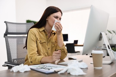 Photo of Sick woman with runny nose at table in office