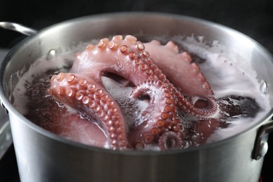 Photo of Fresh octopus boiling in pan on stove, closeup