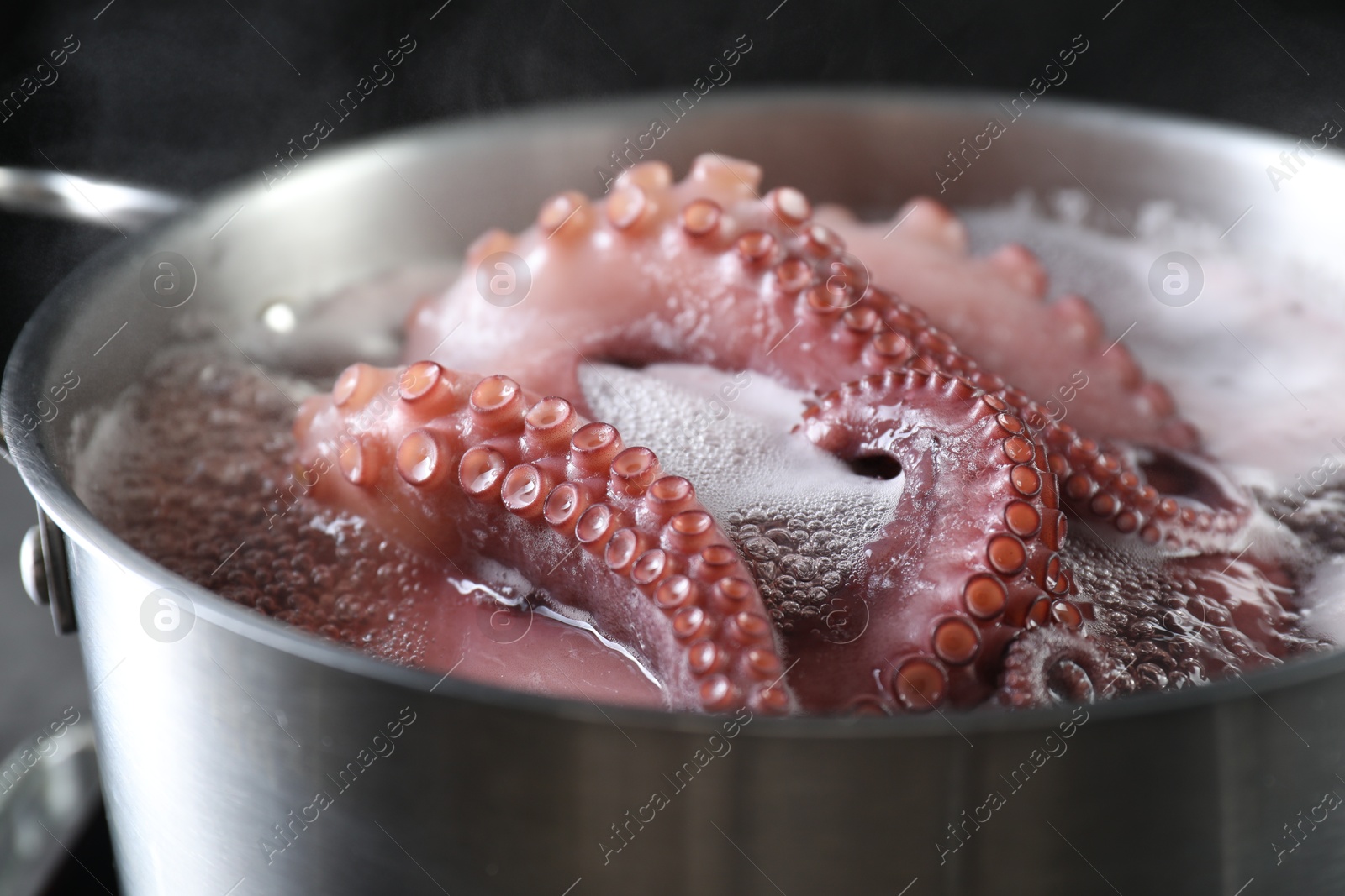 Photo of Fresh octopus boiling in pan on stove, closeup