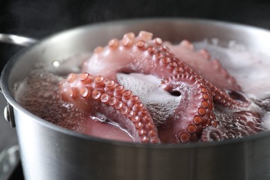 Photo of Fresh octopus boiling in pan on stove, closeup