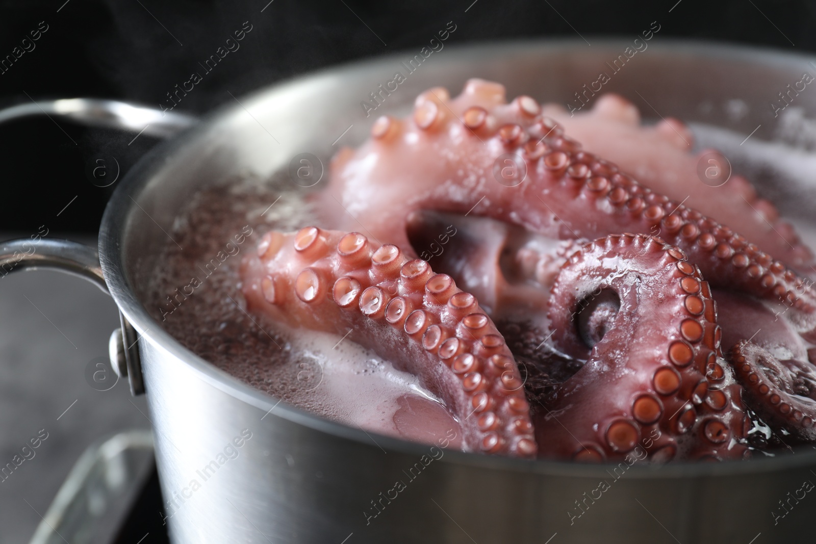 Photo of Fresh octopus boiling in pan on stove, closeup