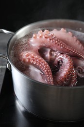 Photo of Fresh octopus boiling in pan on stove, closeup