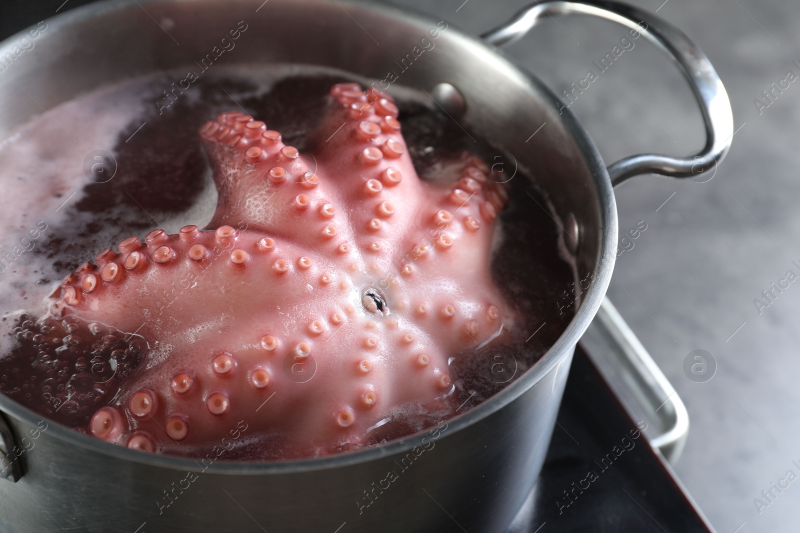 Photo of Fresh octopus boiling in pan on stove, closeup