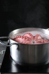 Photo of Fresh octopus boiling in pan on stove, closeup