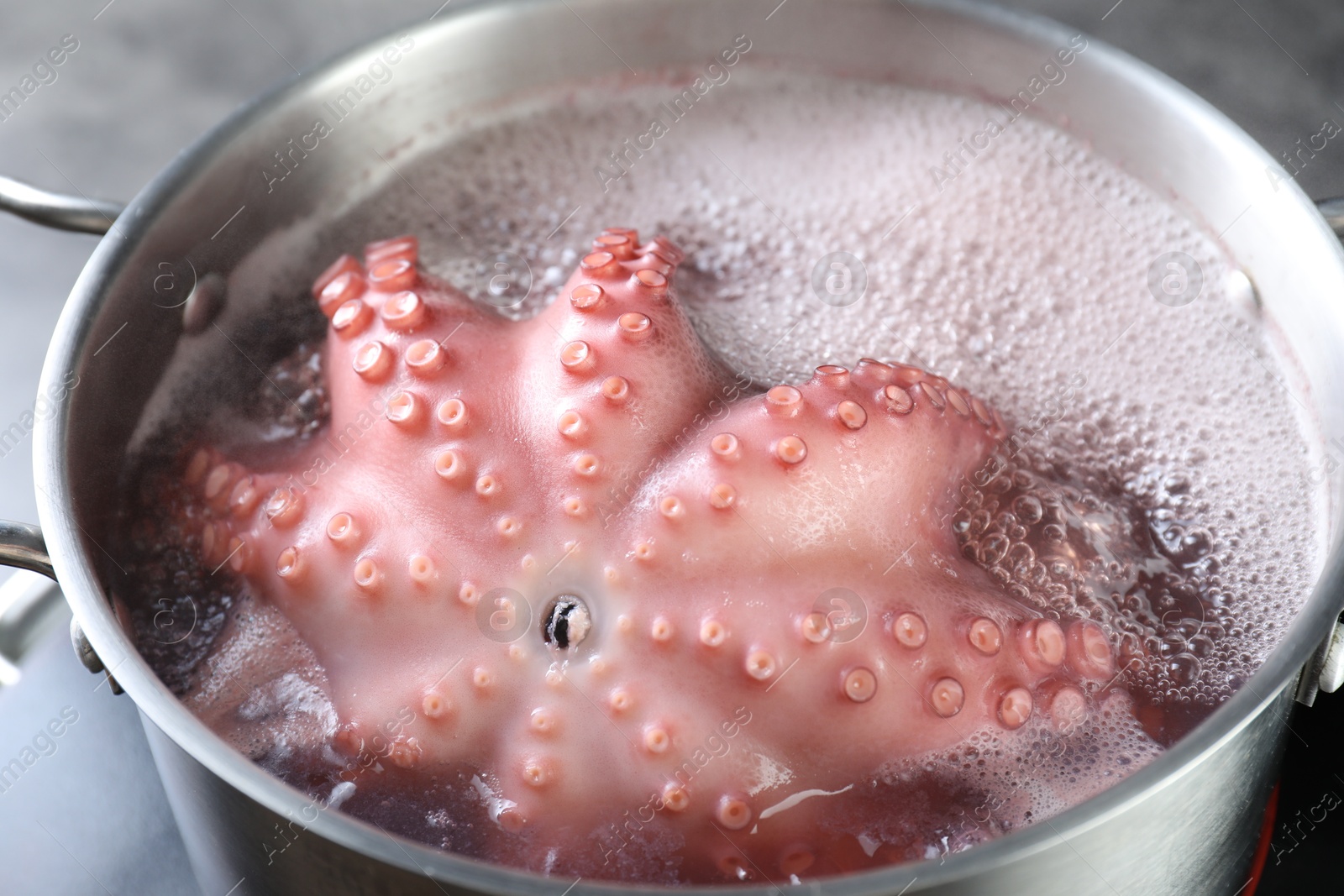 Photo of Fresh octopus boiling in pan on stove, closeup