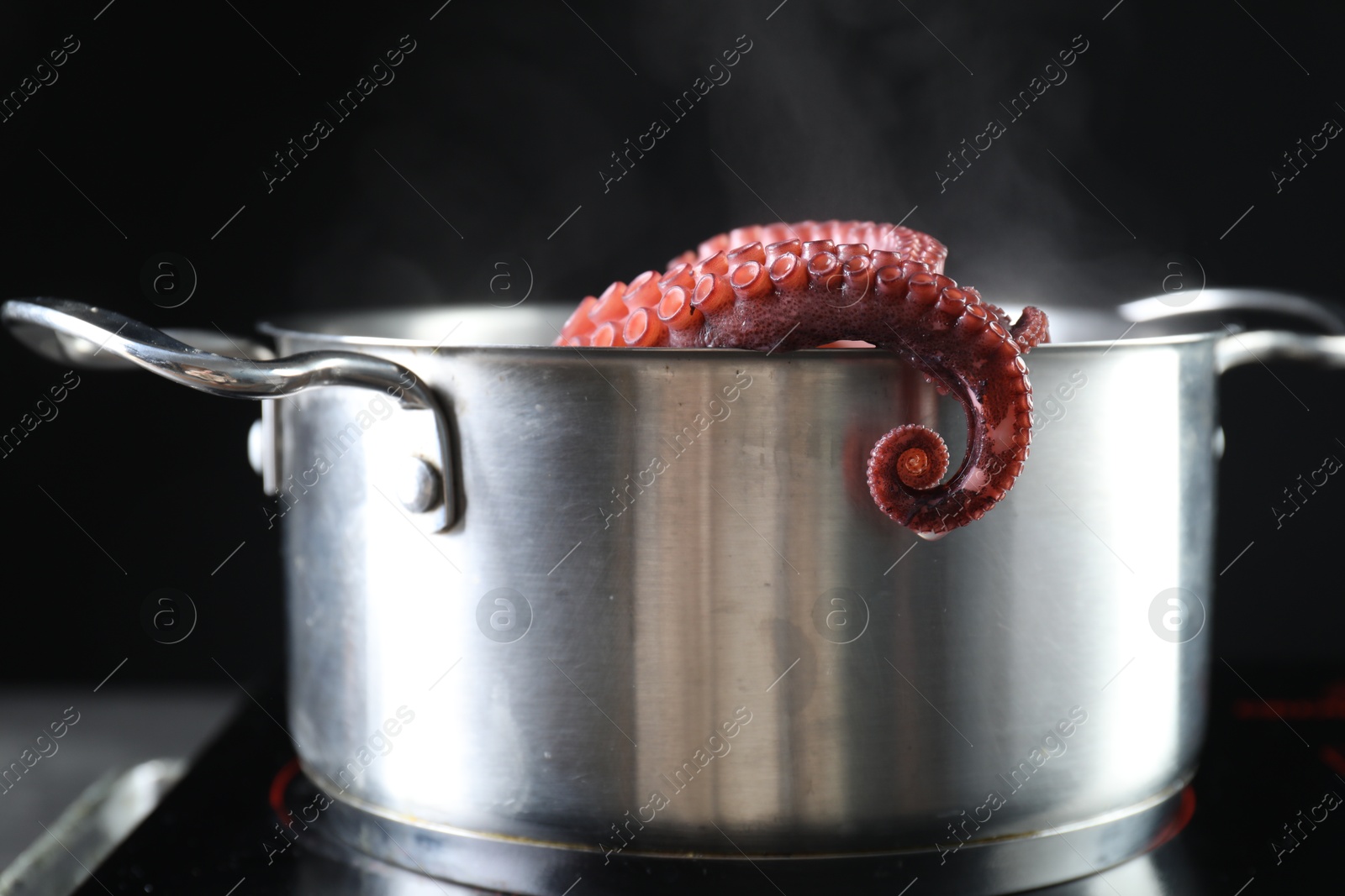 Photo of Fresh octopus boiling in pan on stove, closeup