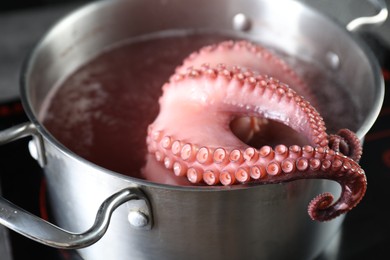 Photo of Fresh octopus boiling in pan on stove, closeup