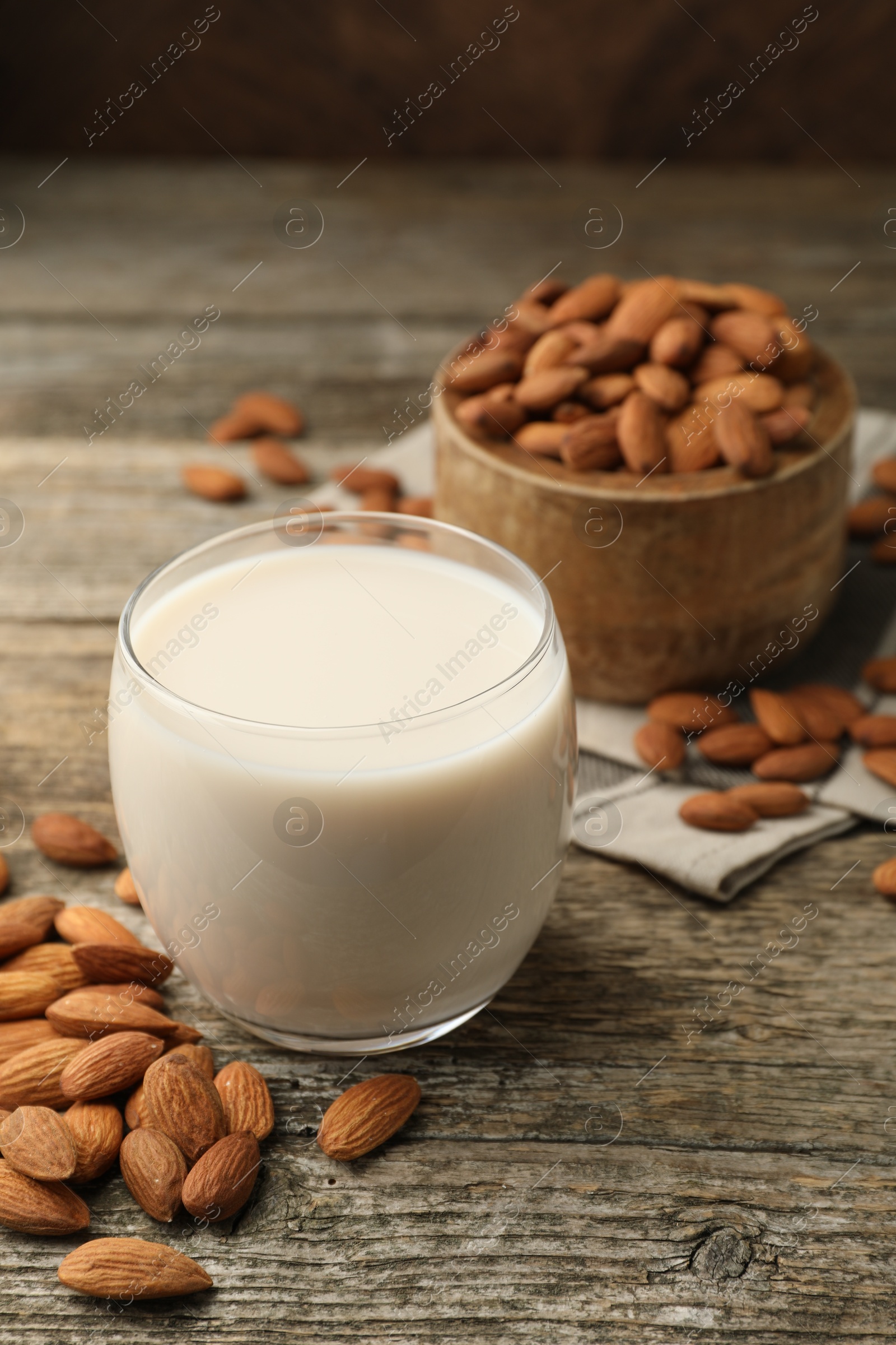 Photo of Fresh almond milk in glass and nuts on wooden table