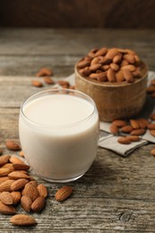 Fresh almond milk in glass and nuts on wooden table