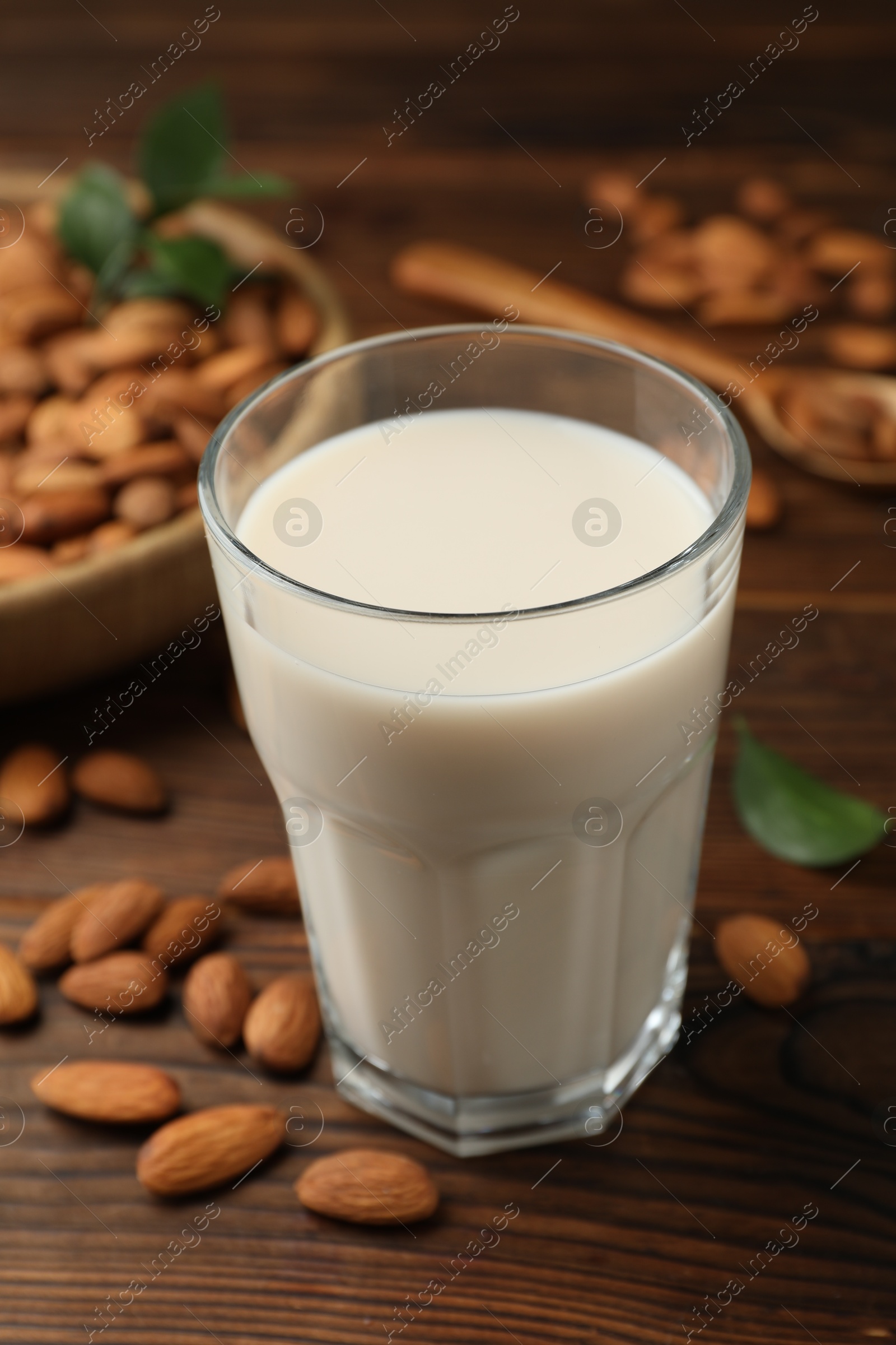 Photo of Fresh almond milk in glass and nuts on wooden table, closeup