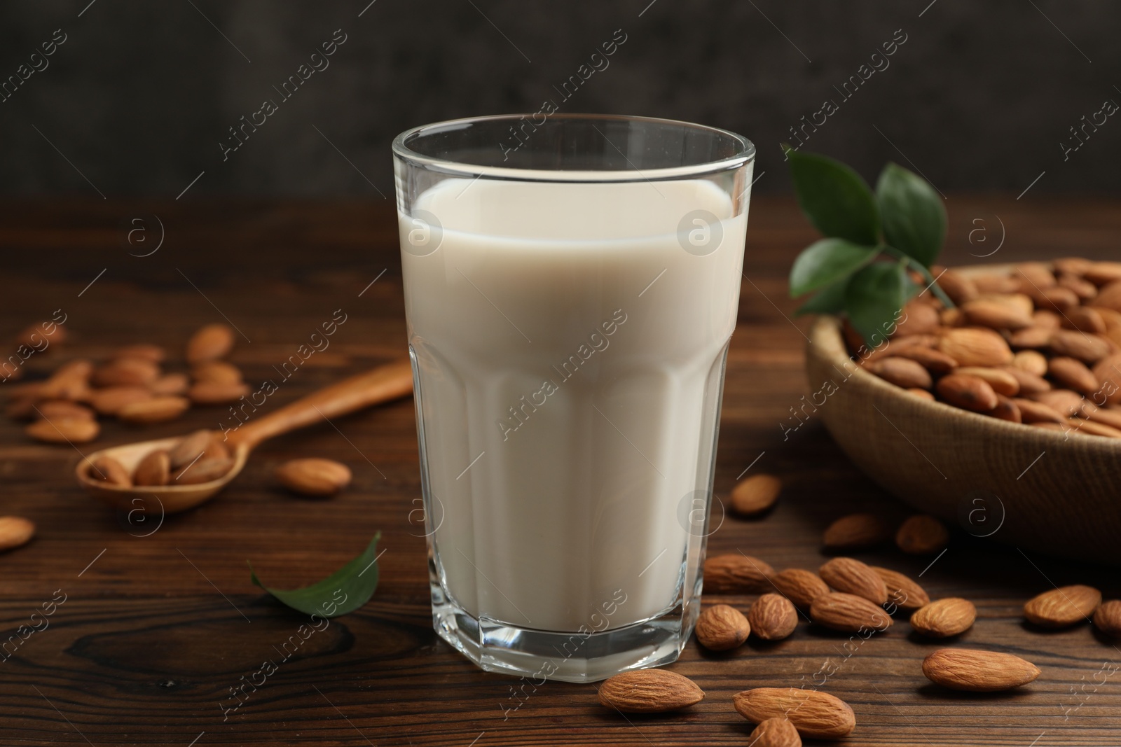 Photo of Fresh almond milk in glass and nuts on wooden table, closeup