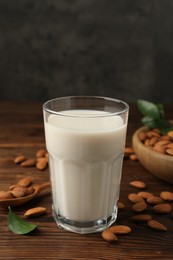 Fresh almond milk in glass and nuts on wooden table