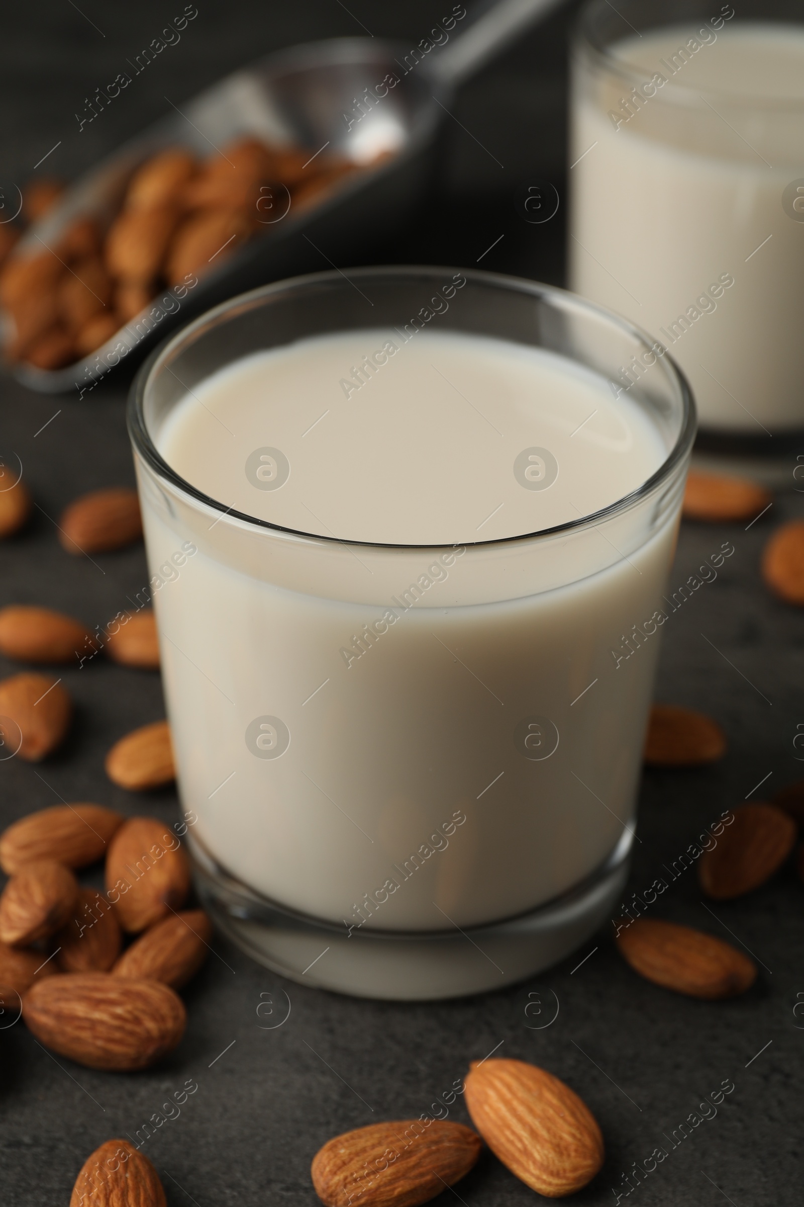 Photo of Fresh almond milk in glasses and nuts on dark grey table, closeup