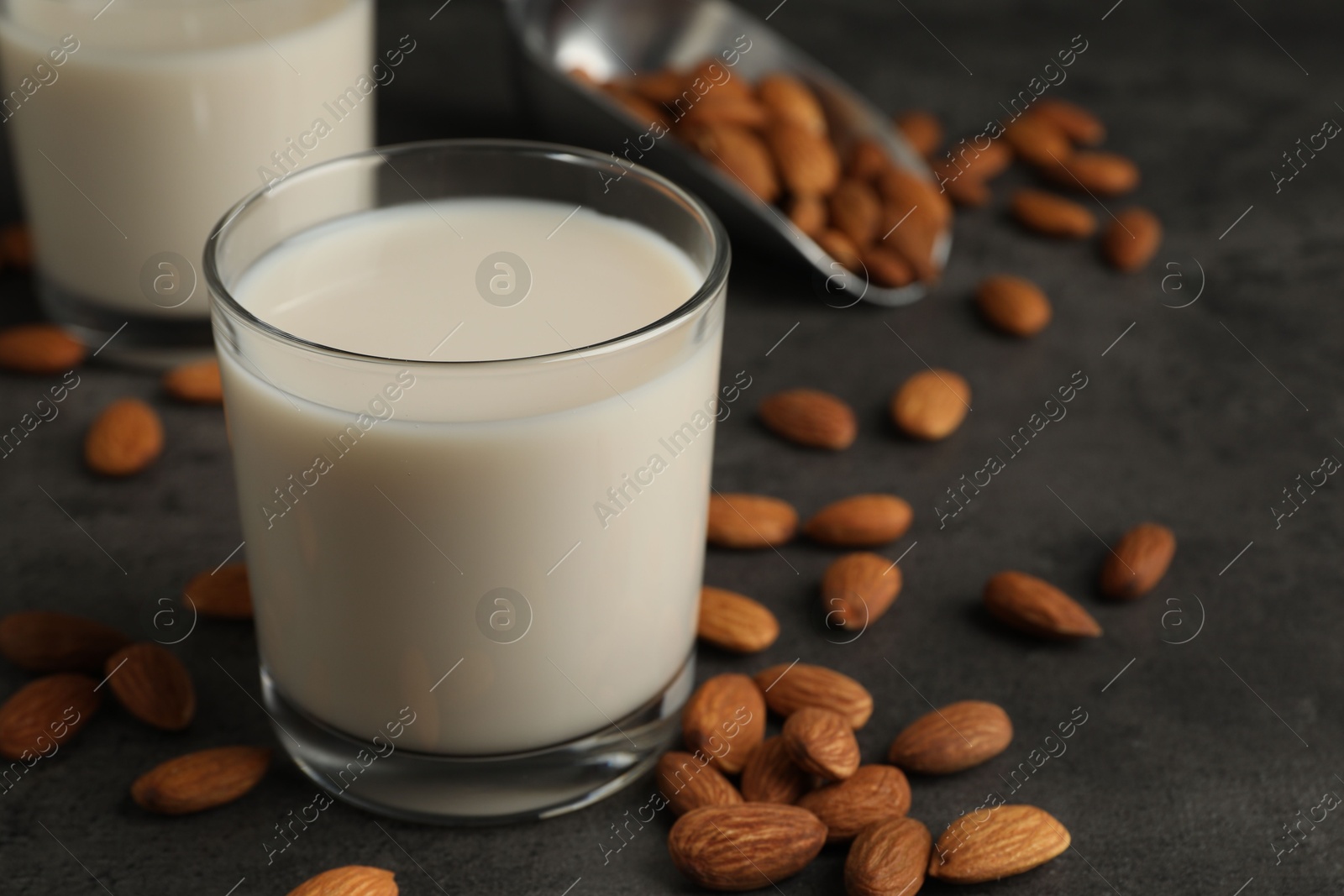 Photo of Fresh almond milk in glasses and nuts on dark grey table, closeup