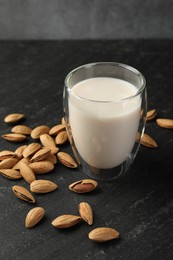 Photo of Fresh almond milk in glass and nuts on black table