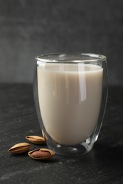 Photo of Fresh almond milk in glass and nuts on black table, closeup