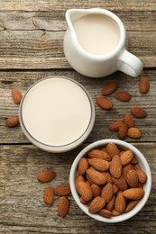 Fresh almond milk and nuts on wooden table, top view