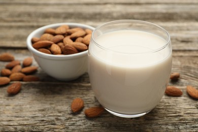 Photo of Fresh almond milk in glass and nuts on wooden table, closeup