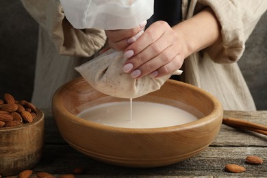 Photo of Woman making almond milk at wooden table, closeup