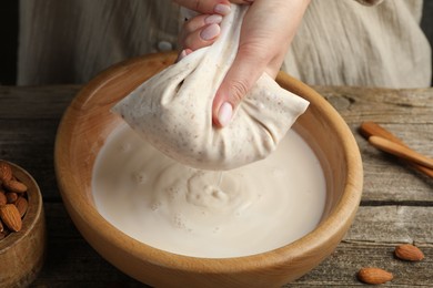 Photo of Woman making almond milk at wooden table, closeup