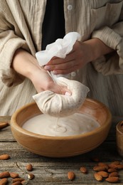 Photo of Woman making almond milk at wooden table, closeup