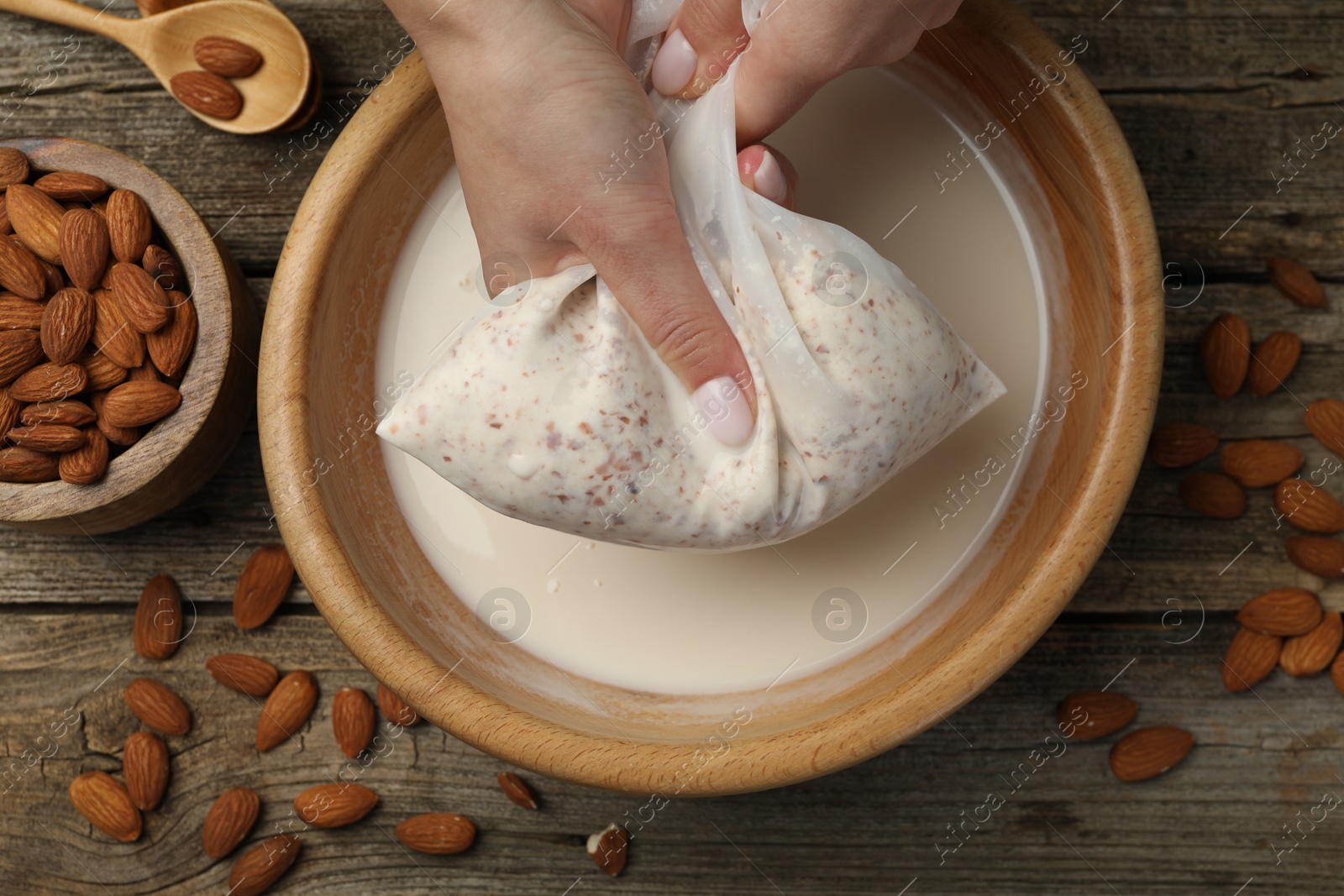 Photo of Woman making almond milk at wooden table, top view