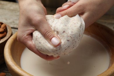 Photo of Woman making almond milk at table, closeup