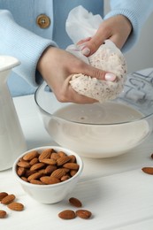 Photo of Woman making almond milk at white wooden table, closeup