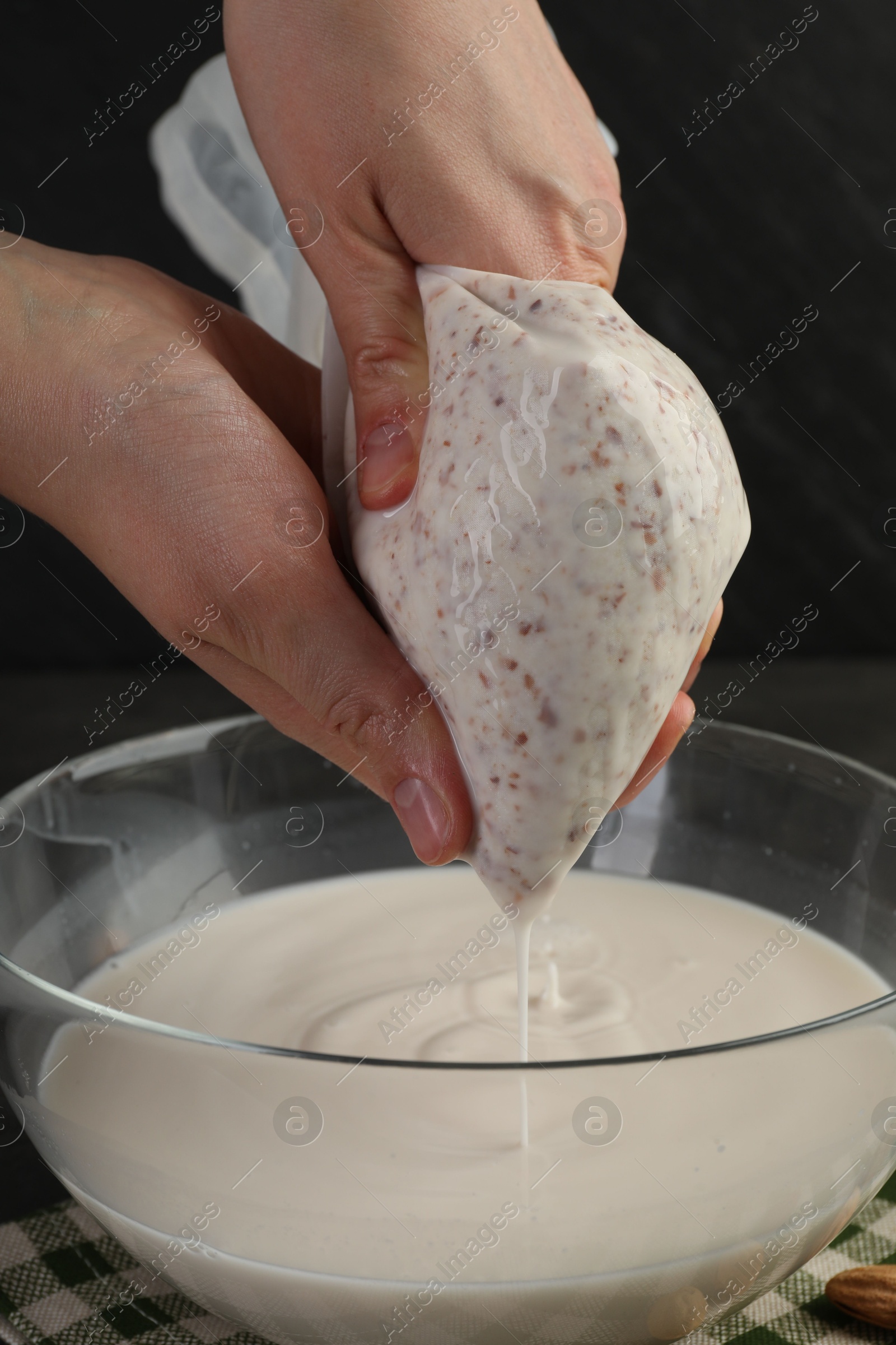 Photo of Woman making almond milk and nuts at table, closeup