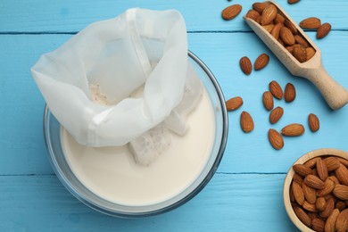 Homemade almond milk, cheesecloth with mixture and nuts on light blue wooden table, top view