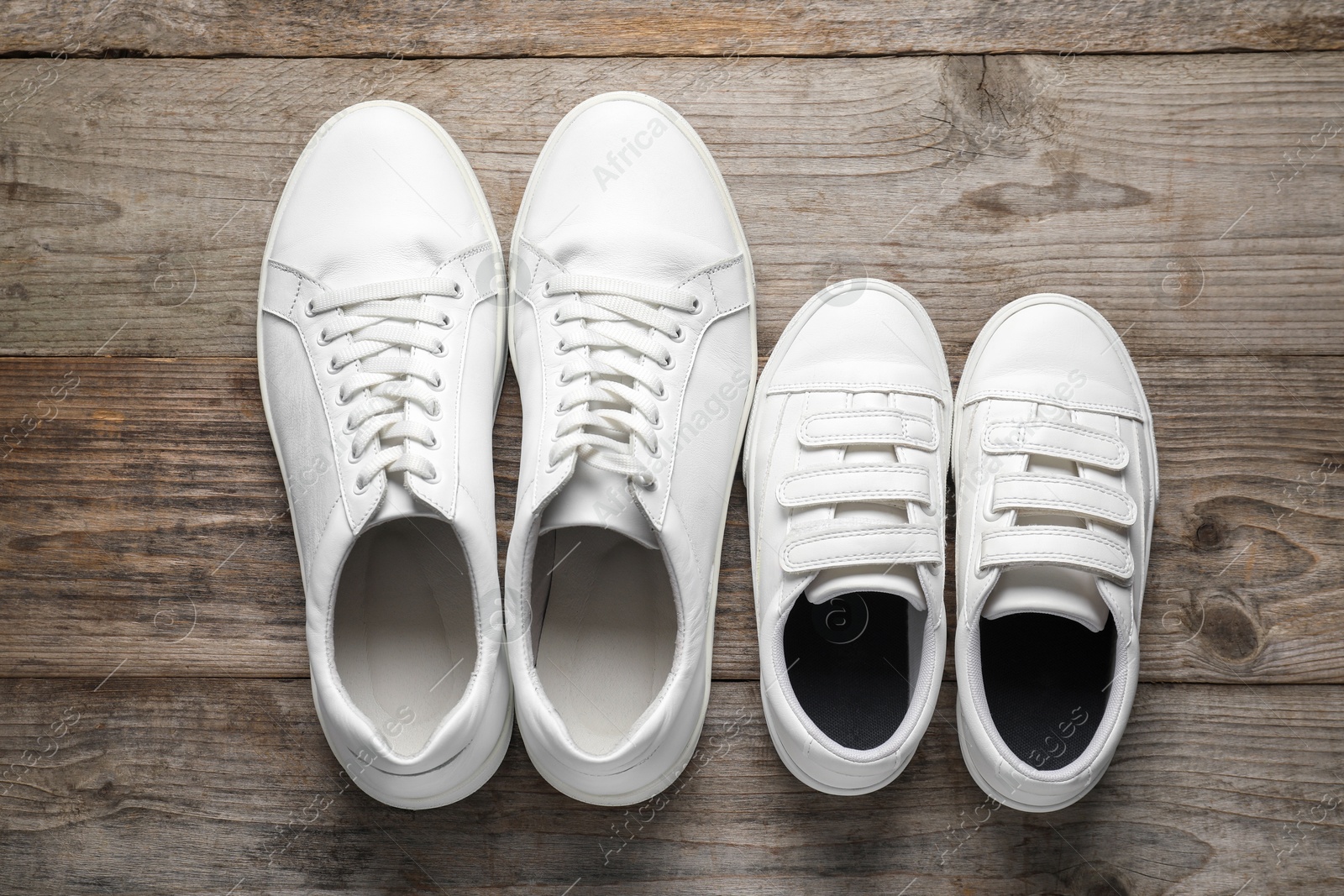 Photo of Big and small shoes on wooden table, top view