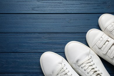 Photo of Big and small shoes on blue wooden table, top view. Space for text