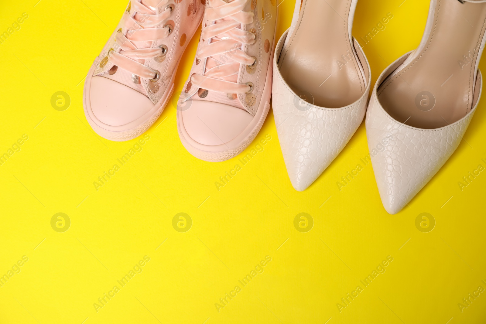 Photo of Big and small shoes on yellow background, top view. Space for text