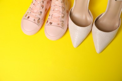 Photo of Big and small shoes on yellow background, top view. Space for text