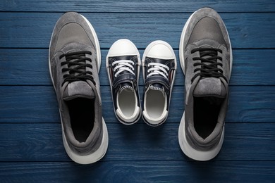 Photo of Big and small shoes on blue wooden table, top view