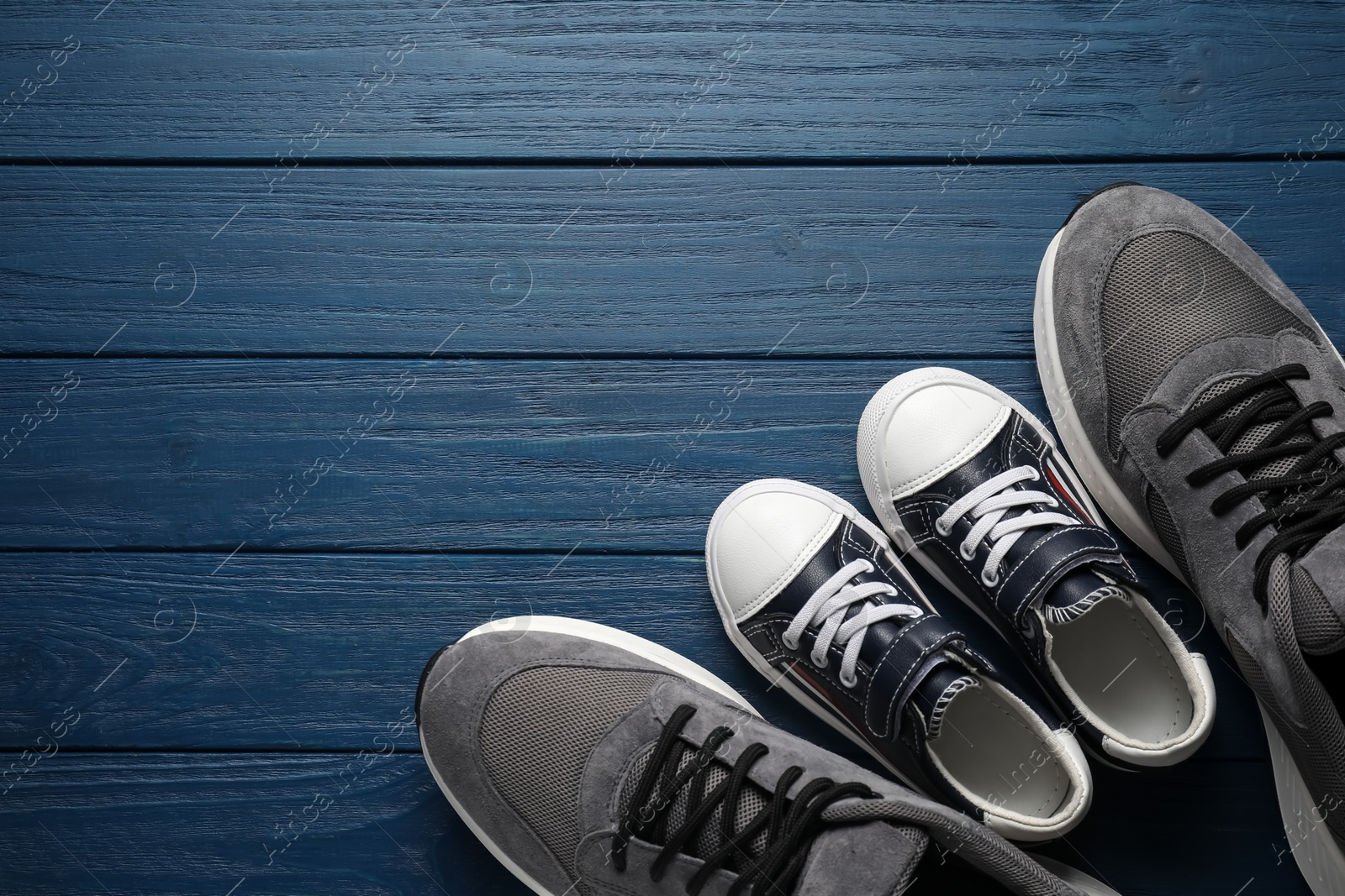 Photo of Big and small shoes on blue wooden table, top view. Space for text