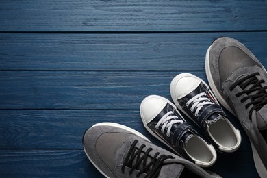 Photo of Big and small shoes on blue wooden table, top view. Space for text