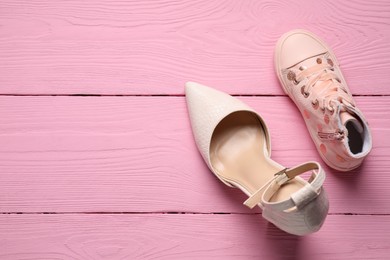 Photo of Big and small shoes on pink wooden table, top view. Space for text