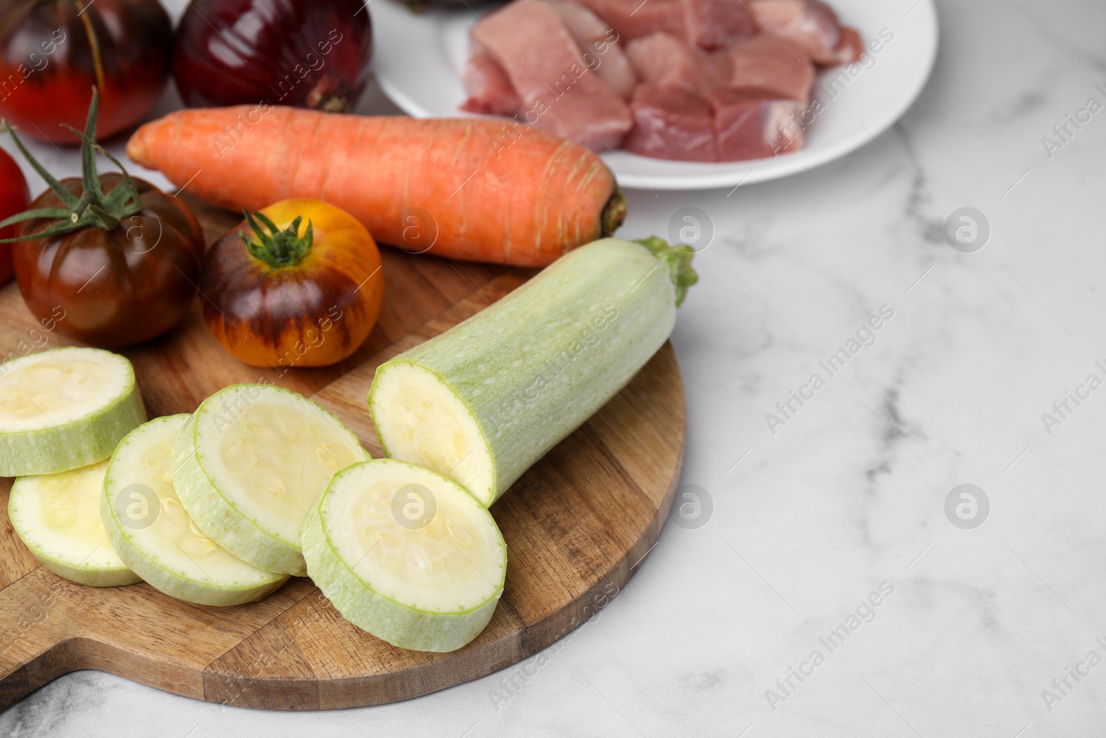 Photo of Different vegetables and raw meat for stew on white marble table, space for text