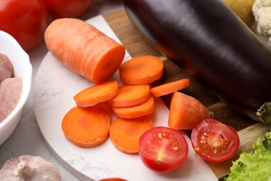 Photo of Cooking tasty stew. Cut carrot, tomato and eggplant on table