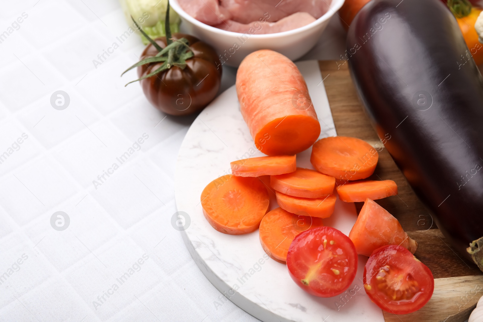 Photo of Different vegetables and raw meat for stew on white tiled table, space for text